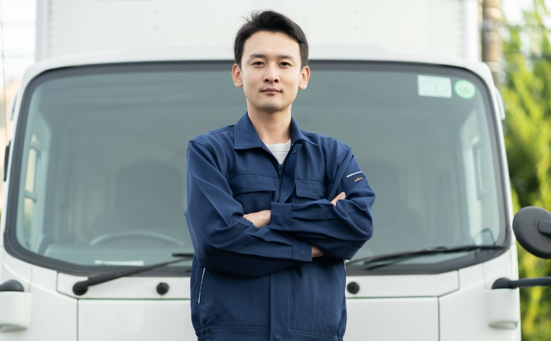 トラックの前で腕を組んでいる男性
